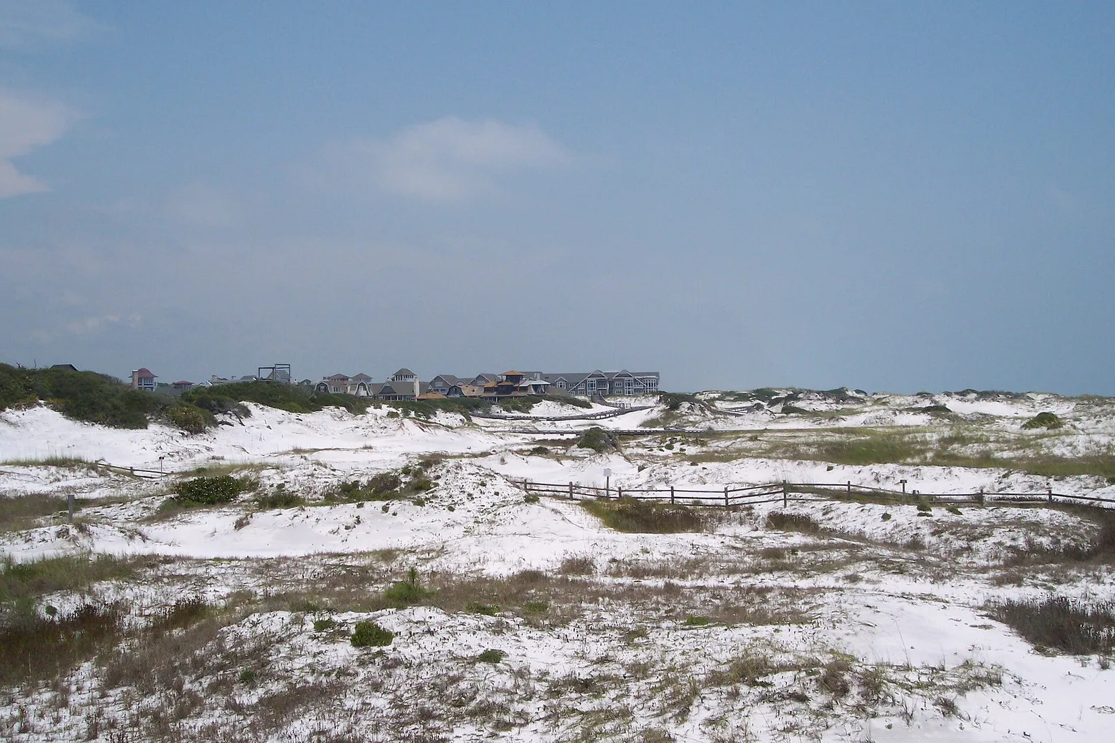 Rolling white sand dunes with low scrub and a dune fence at Deer Lake State Park