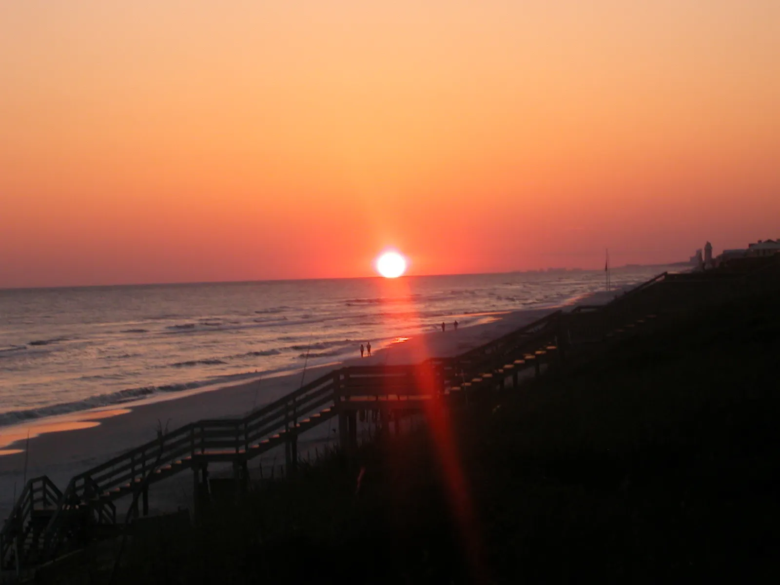 Orange sun setting over the Gulf beside a beach walkover at Rosemary Beach