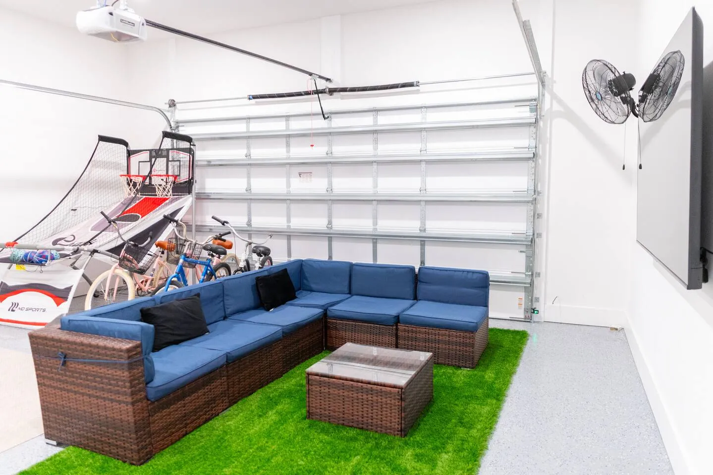 Garage lounge at Harbor Heights with a sectional sofa, TV and bicycles hanging on the wall