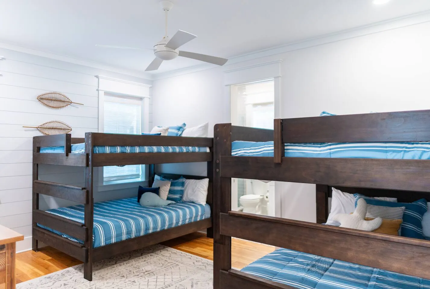 Bunk room with two sets of built-in bunk beds, white bedding and a coastal blue accent wall at Harbor Heights